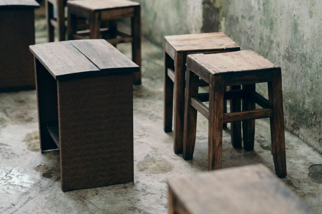 Rustic wooden chairs and tables in a weathered vintage interior, creating a nostalgic atmosphere.