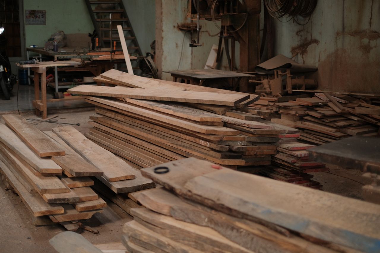 testimonial-image Pile of wooden planks stacked in a rustic workshop, showcasing carpentry and craftsmanship.