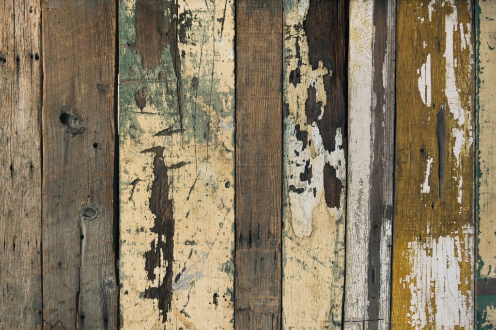 Close-up of textured, weathered wooden planks with peeling paint, showcasing rustic charm.